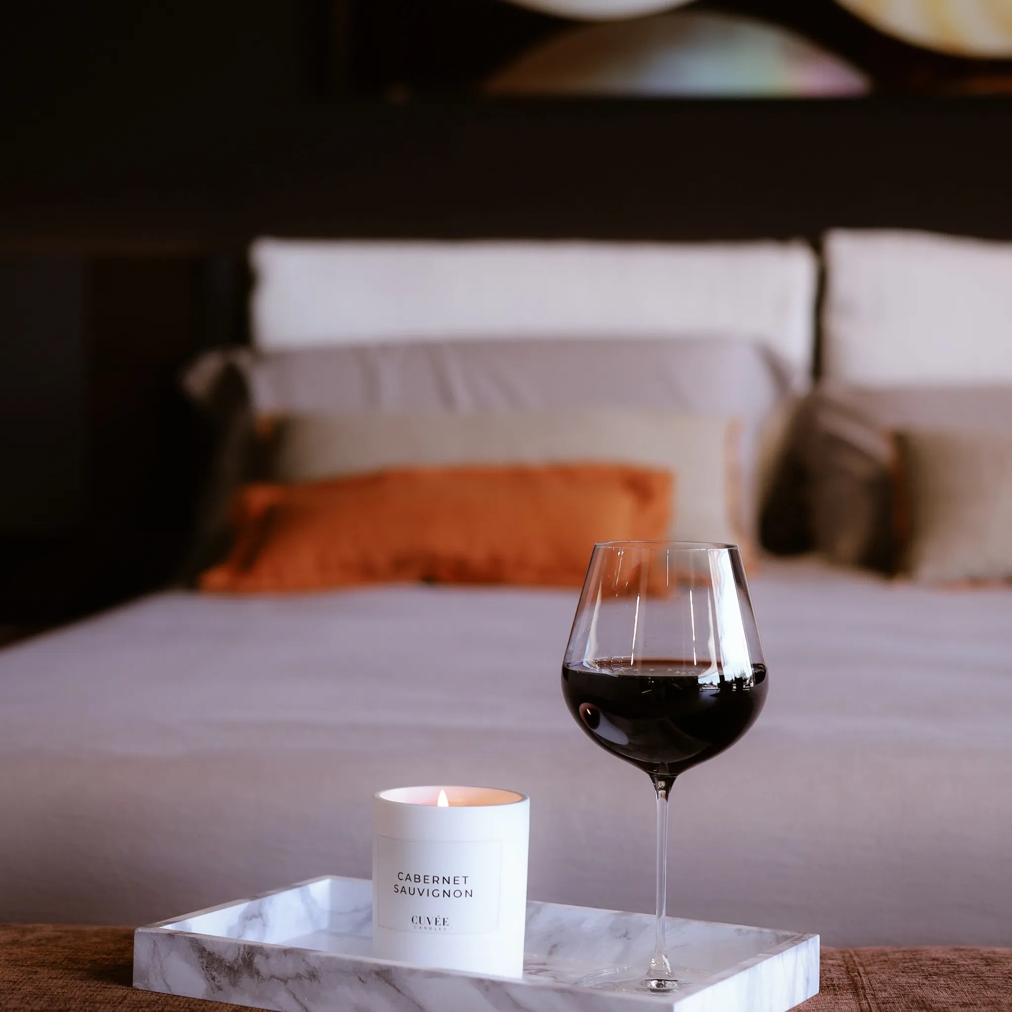 CUVÉE Duftkerze Cabernet Sauvignon auf einem Marmortablett neben einem Glas Rotwein