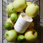 CUVÉE Duftkerze Riesling in einem Drahtkorb voller grüner Äpfel