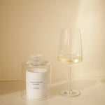 CUVÉE Duftkerze Sauvignon Blanc unter einer Duftglocke aus Glas neben einem Glas Weißwein