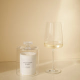 CUVÉE Duftkerze Sauvignon Blanc unter einer Duftglocke aus Glas neben einem Glas Weißwein