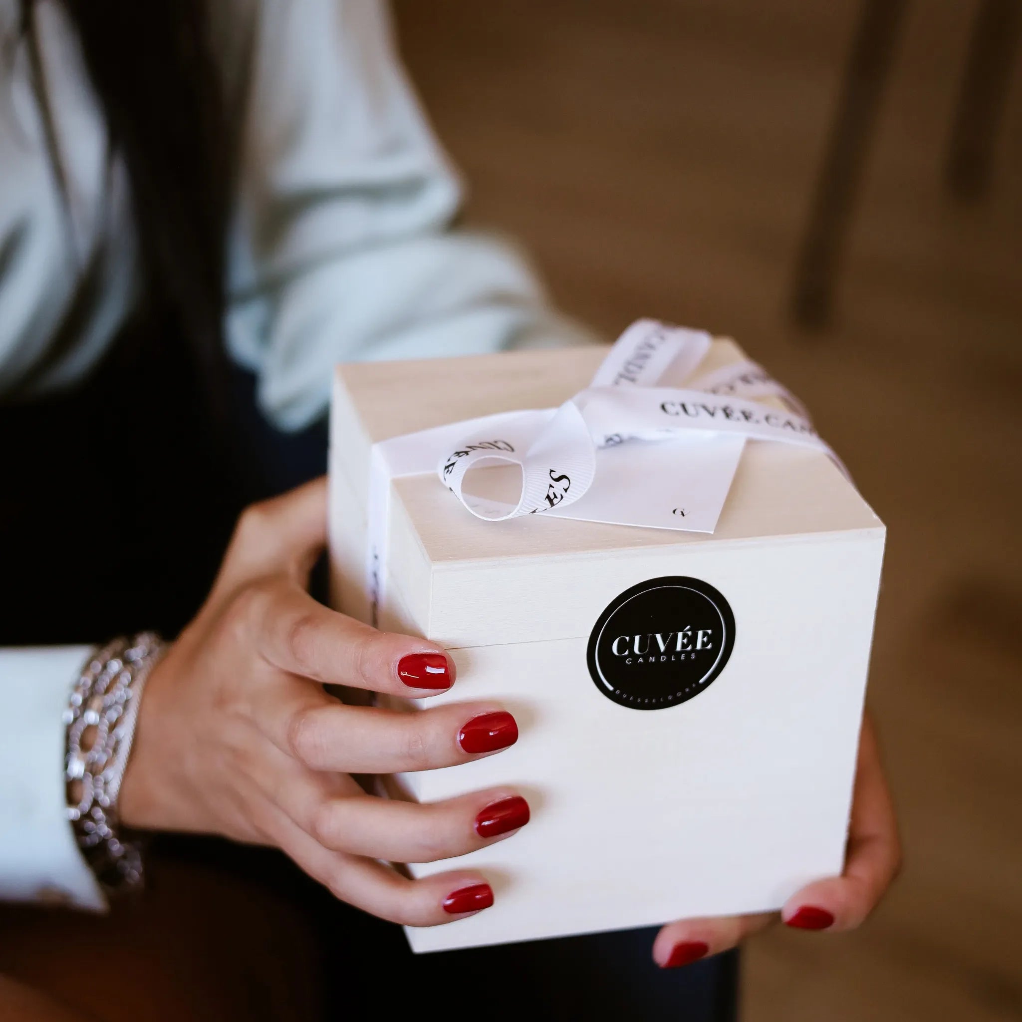 Hände halten eine weiße CUVÉE Geschenkbox mit Schleife als Gastgeschenk